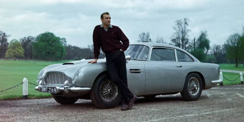 Sean Connery leaning onto an Aston Martin DB-5 in a promotion still for Goldfinger