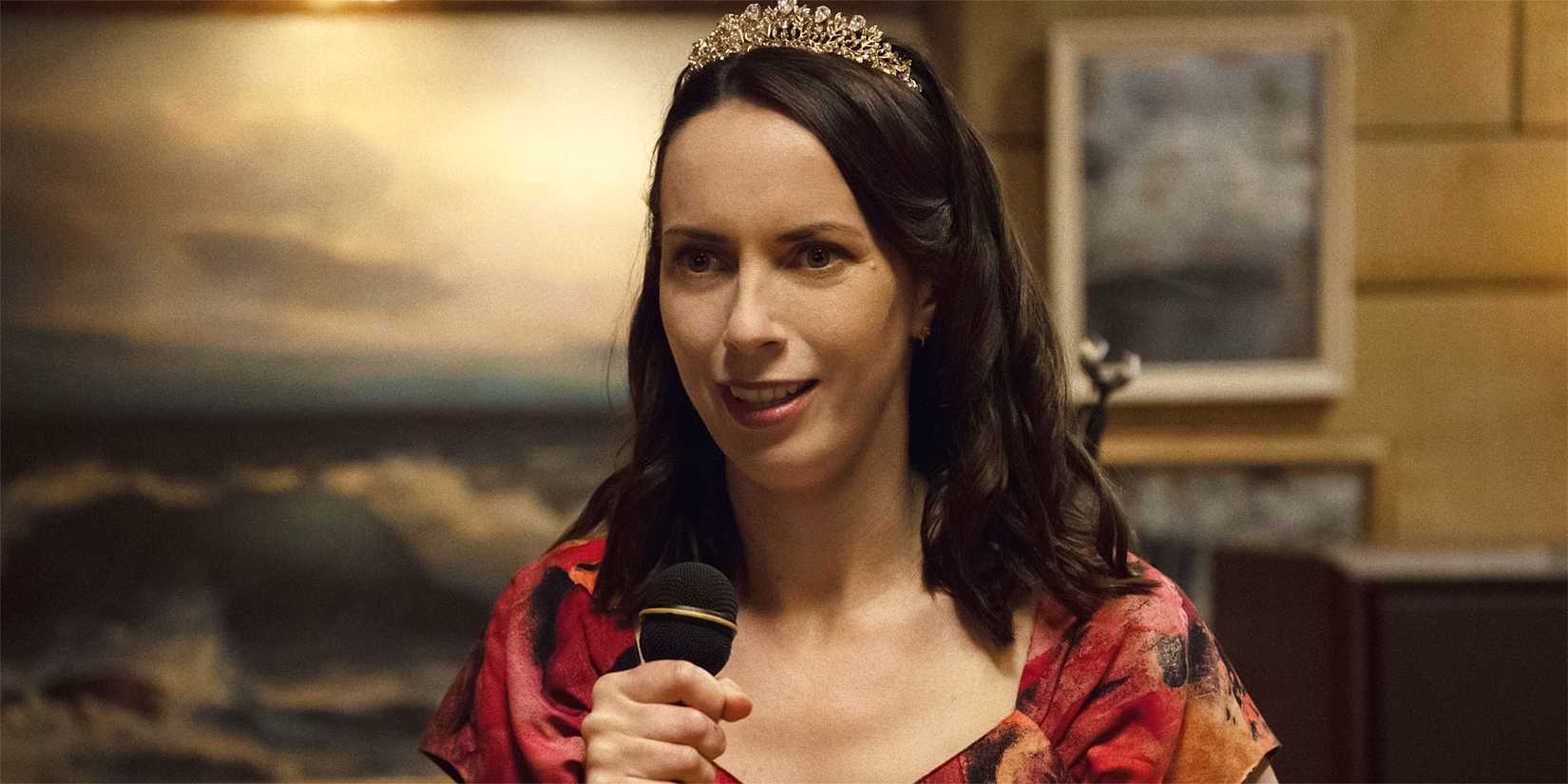 Patricia in a tiara and holding a microphone in Widow's Bay.