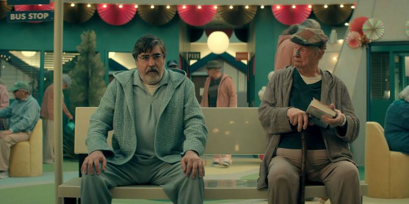 Alfred Molina sits next to Robert Benedetti at a fake bus stop inside a care center in The Boroughs