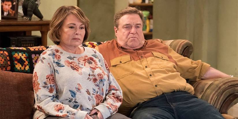 Roseanne and Dan sitting together on the couch in The Conners.