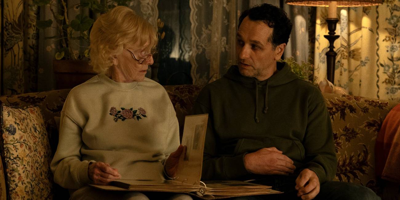 Matthew Rhys as Tom sitting on a couch next to K Callan as Ruth in Widow's Bay