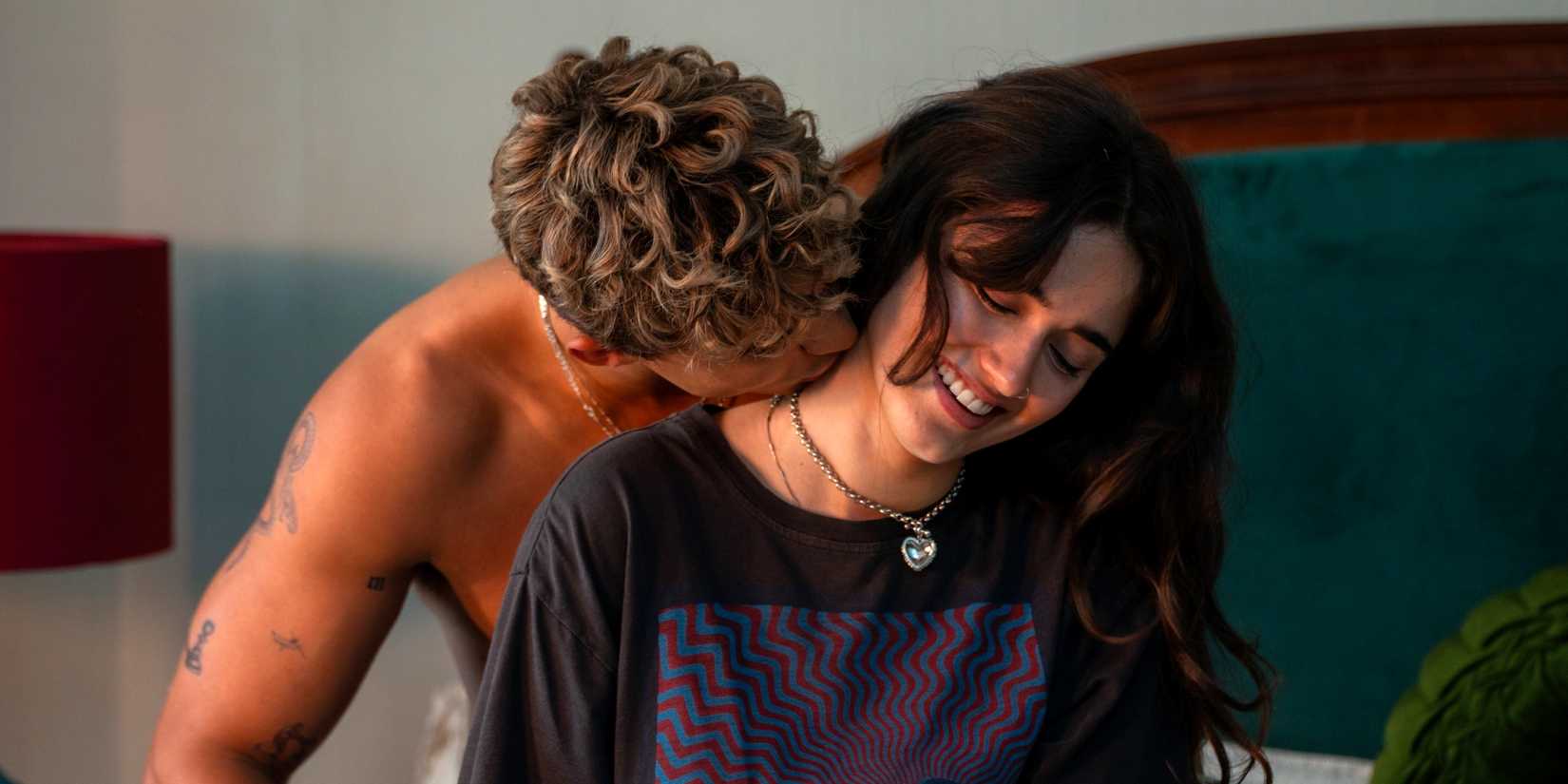 Matthew Broome as Nick sitting on the bed behind Asha Banks as Noah and kissing her neck in Your Fault: London