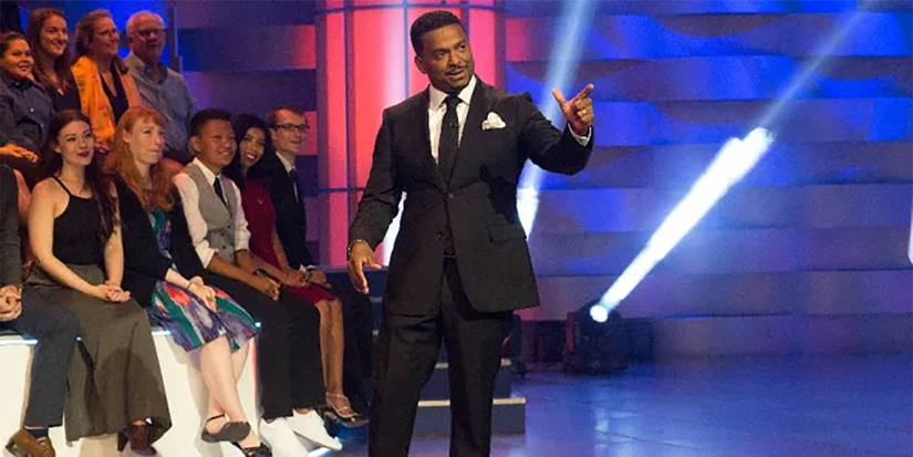 Alfonso Ribeiro on stage pointing to something as audience members look on in America's Funniest Home Videos.