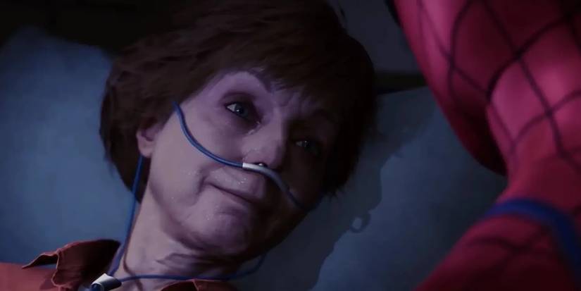Aunt May laying on a hospital bed with tubing coming out of her nose while Spider-Man looks at her during her death scene in Marvel's Spider-Man for PS4