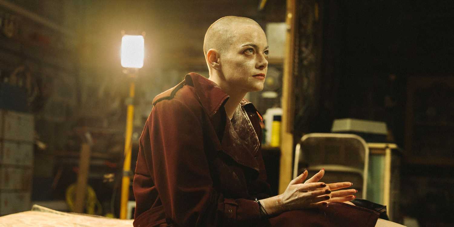 Emma Stone with a shaved head tethered to a bed in a basement in Bugonia