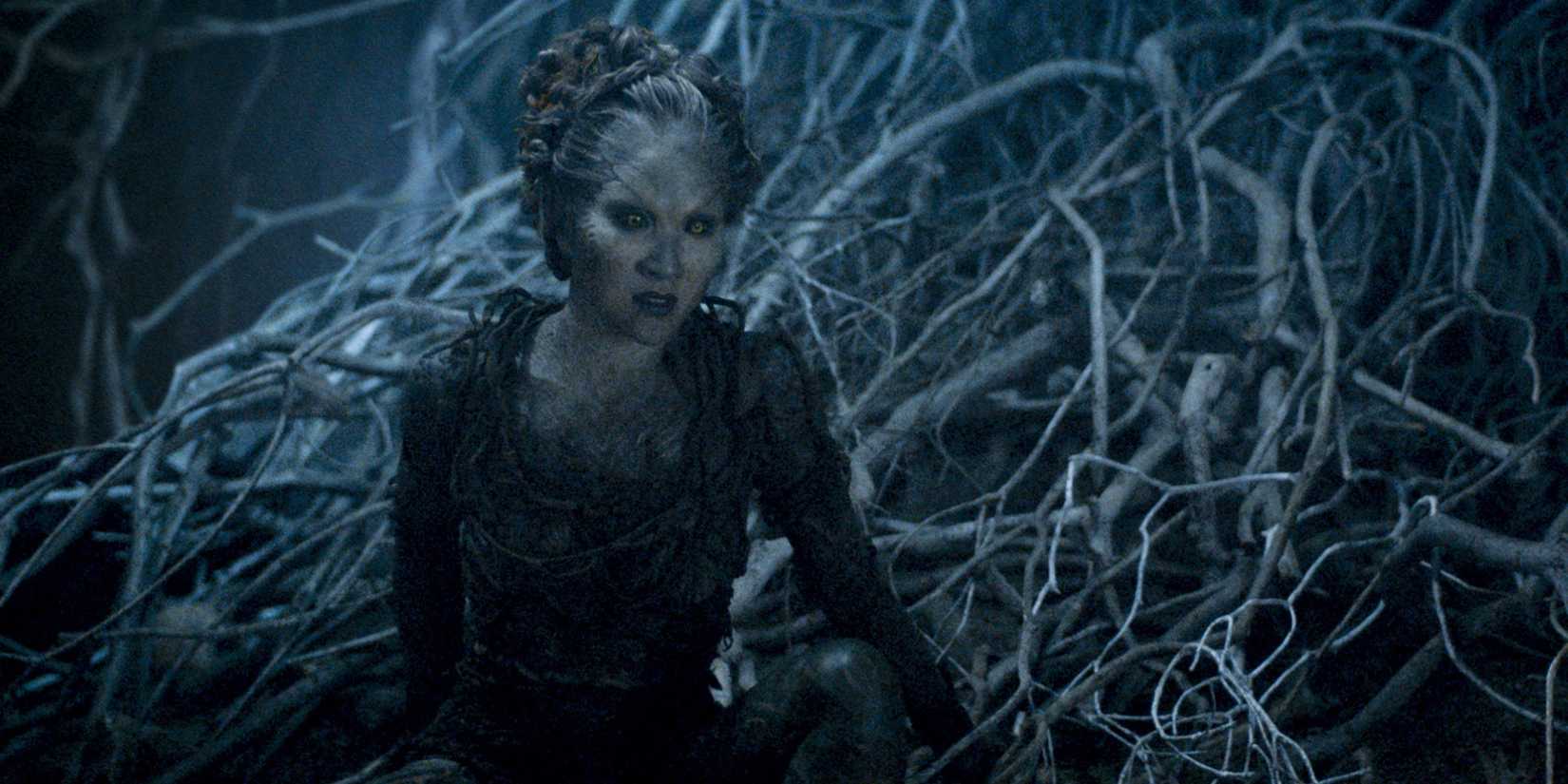 Kae Alexander as Leaf in Game of Thrones, sitting among a tangle of Weirwood roots.