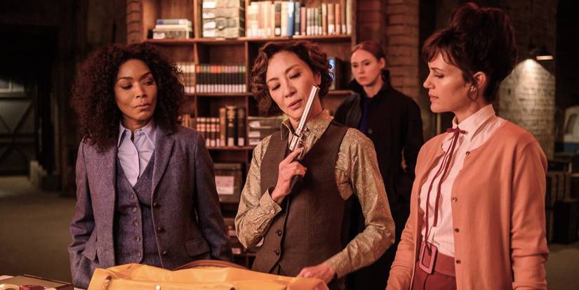 Angela Bassett, Karen Gillan, Michelle Yeoh, and Carla Gugino examine guns and other weapons in a library in Gunpowder Milkshake