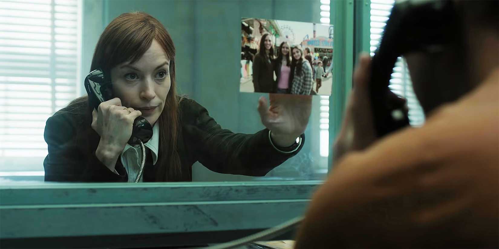 Britt Lower holding up a picture to the glass in 'I Will Find You'