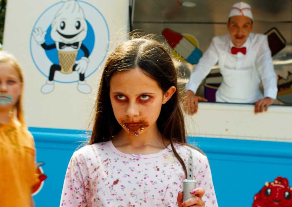 A killer kid stands in front of the Ice Cream Man in 'Ice Cream Man'