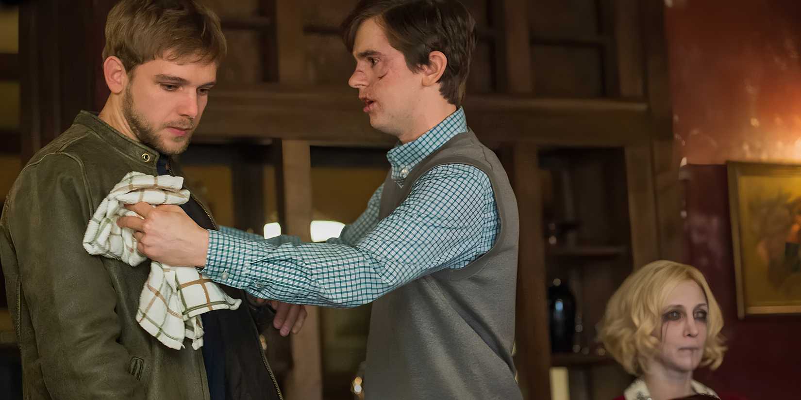 Norman (Freddie Highmore) wipes off Dylan's (Max Thieriot) jacket as Norma's (Vera Farmiga) body is sitting behind in Bates Motel.