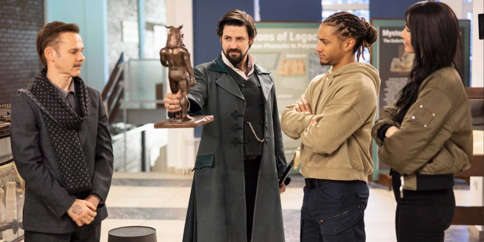 Merlin (Dominic Monaghan) stands beside Vikram Chamberlain (Callum McGowan), Connor Green (Bluey Robinson), and Charlie Cornwall (Jessica Green) with the demon idol on 'The Librarians: The Next Chapter'
