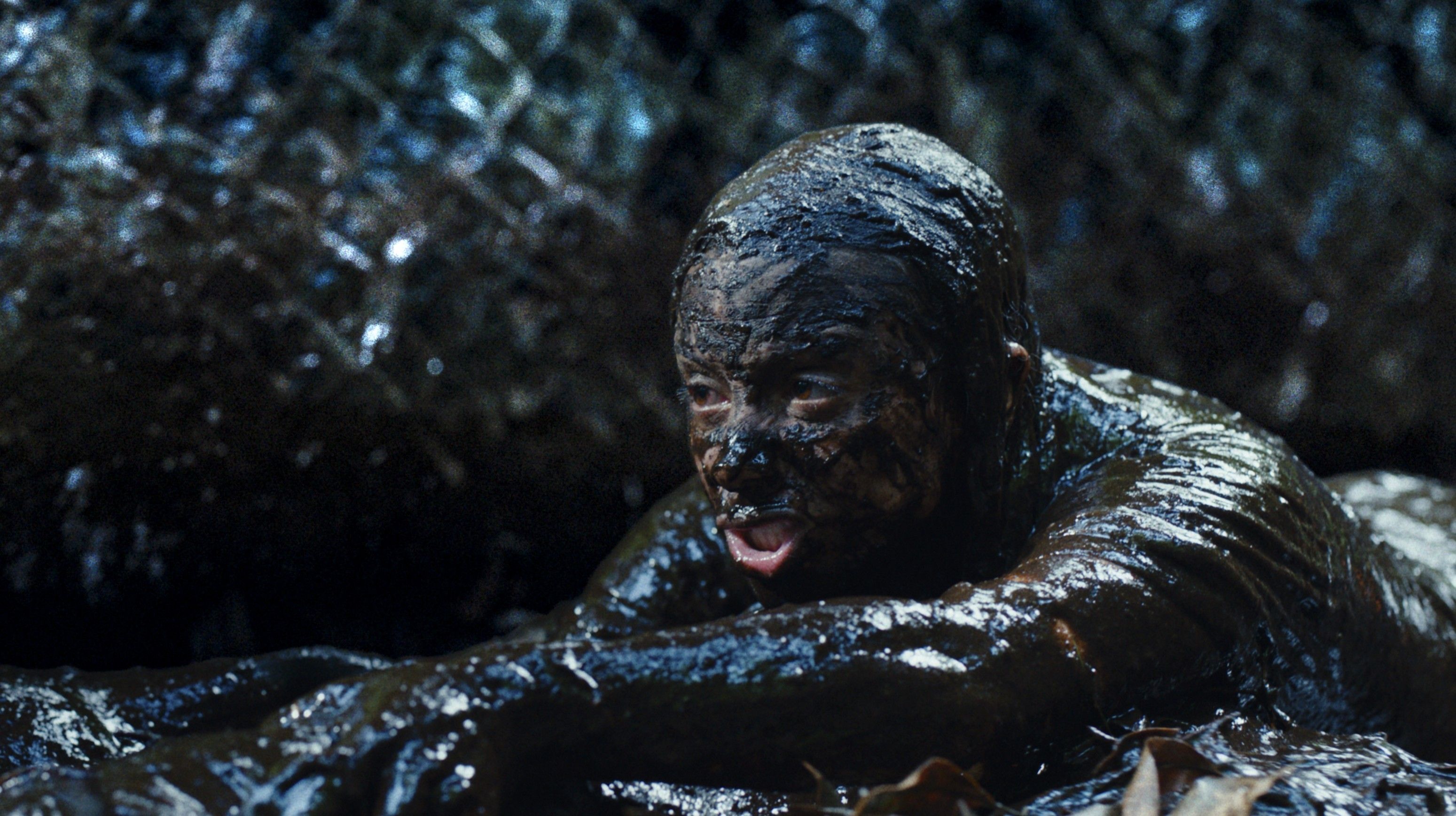 A person drenched in mud with a serpent drapped around their neck in Beware Boiuna