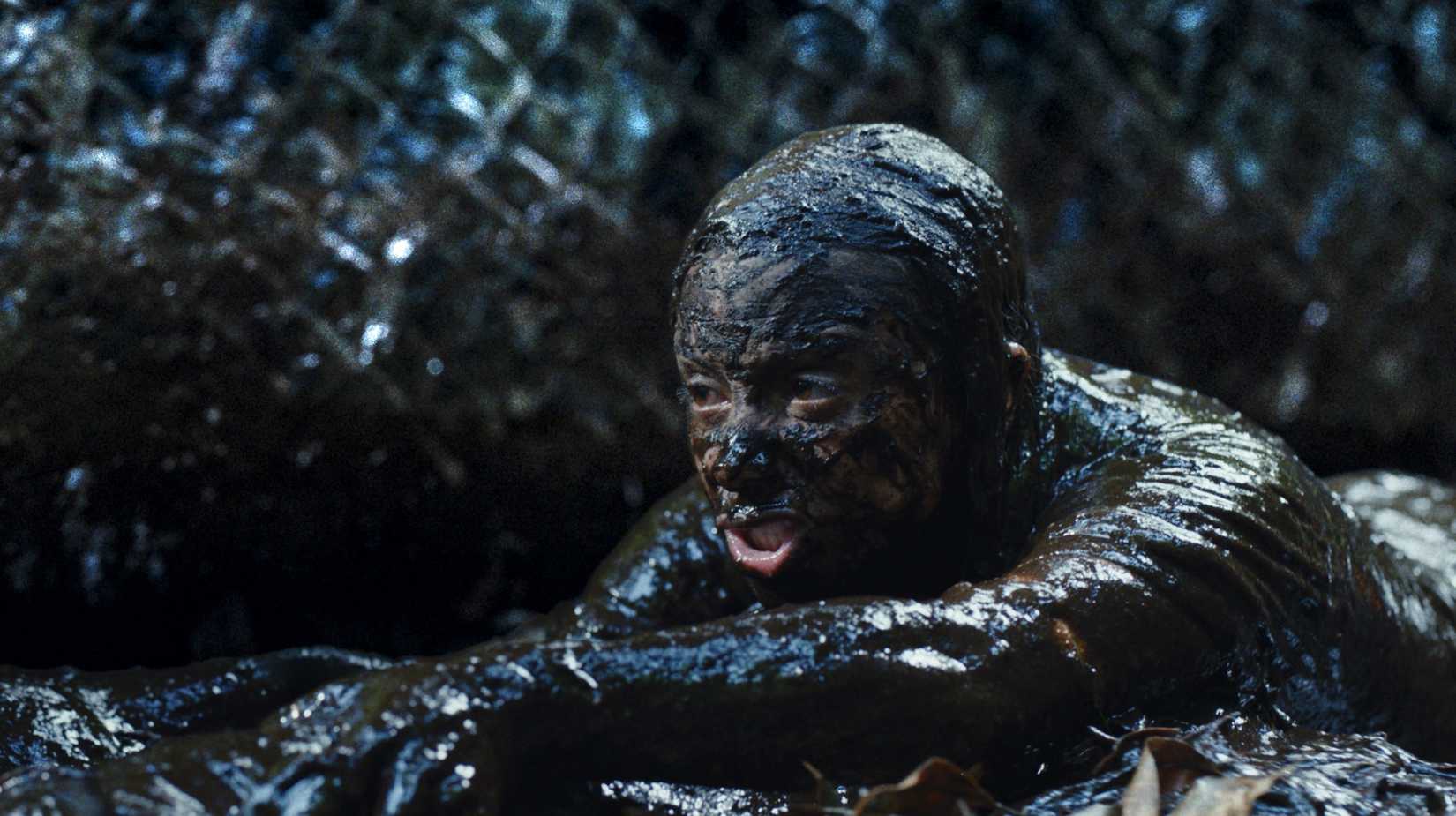 A person drenched in mud with a serpent drapped around their neck in Beware Boiuna