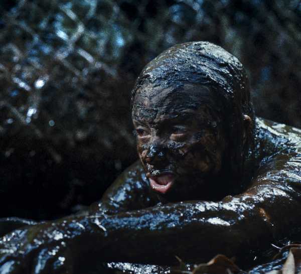 A person drenched in mud with a serpent drapped around their neck in Beware Boiuna