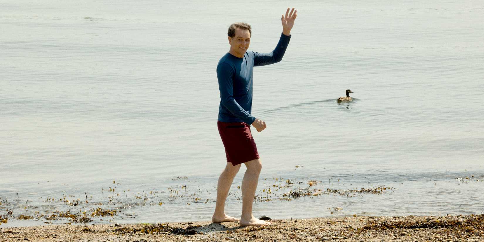 Matthew Rhys as Tom in Widows Bay, waving at the edge of the water.