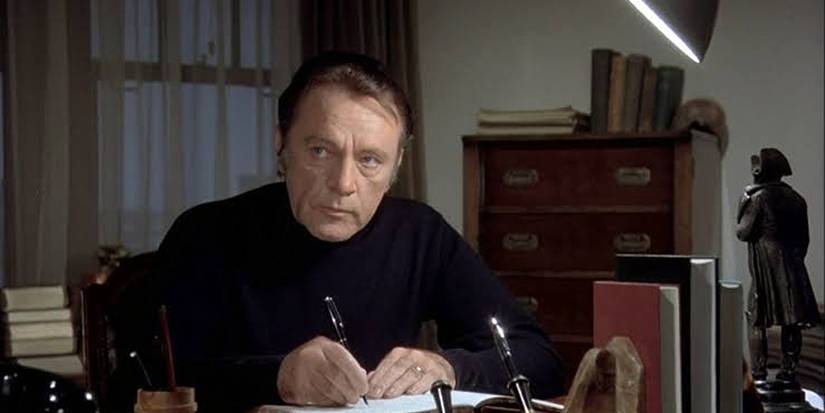 Richard Burton writing something and looking to his right in medusa