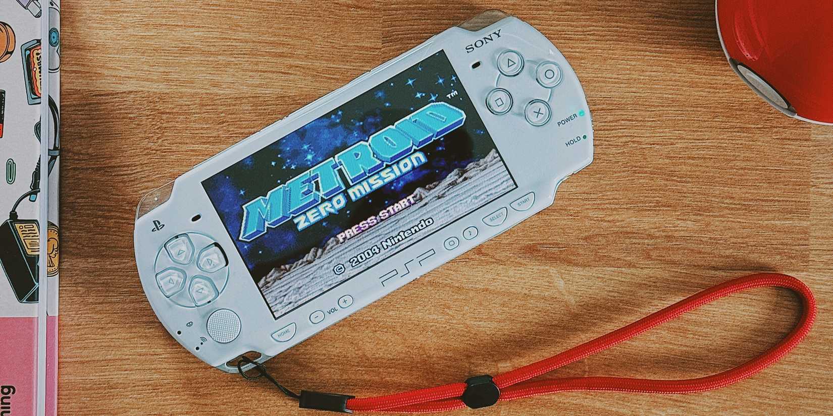 PlayStation Portable (PSP) with a red strap on a table