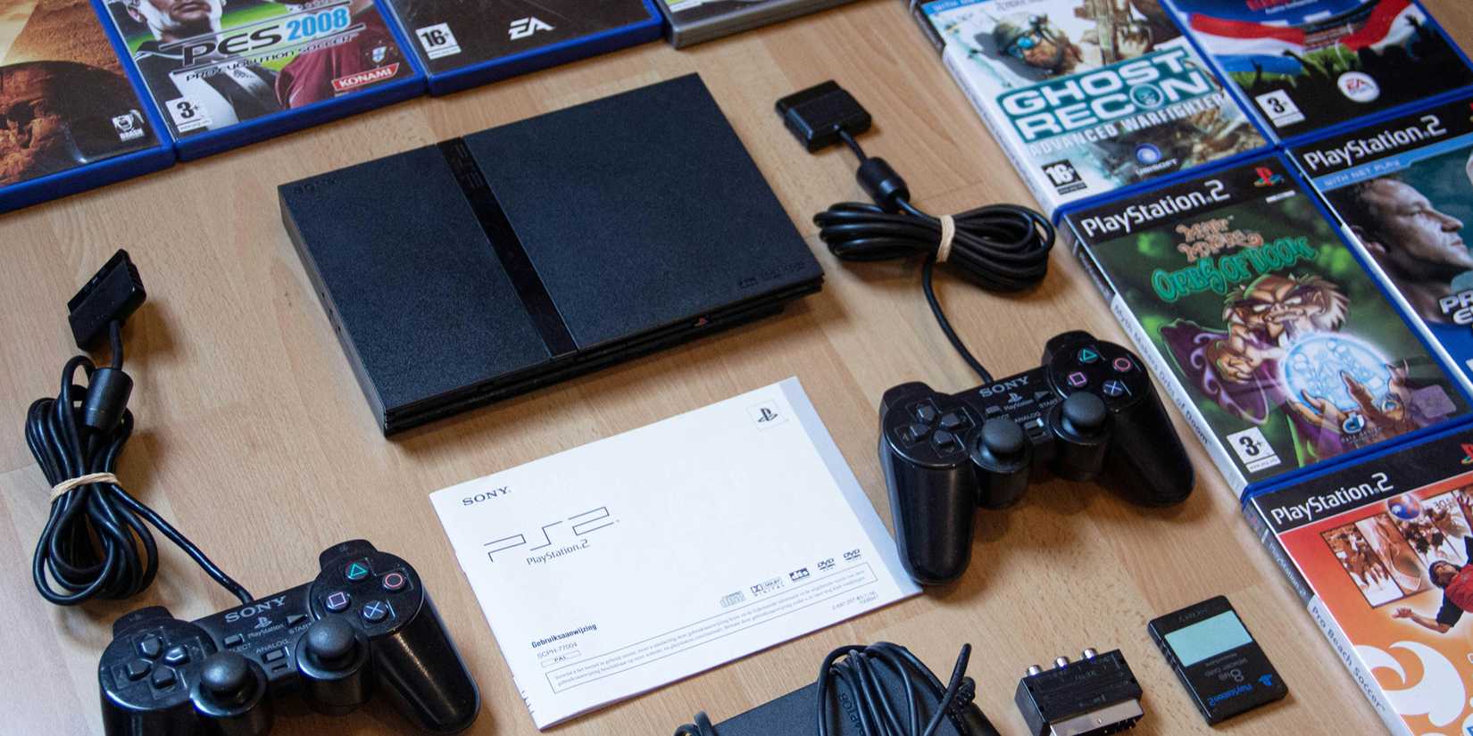 PlayStation 2, controller, and games laid flat on a table