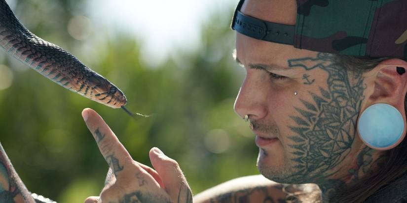 A reptile collector holds an indigo snake in the documentary Monsters of God.
