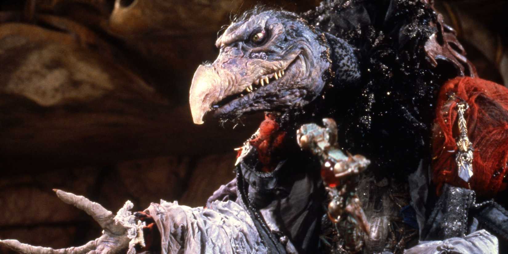 A vulture like Skeksis snarls and reaches an outstretched hand in The Dark Crystal