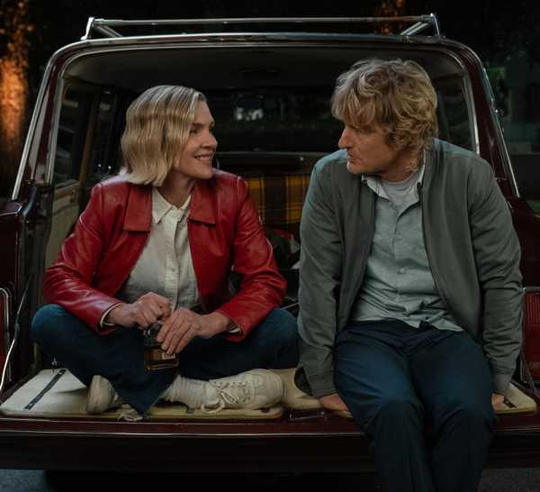 Rhea Seehorn sitting with Owen Wilson in the open back of a car in Stick Season 2