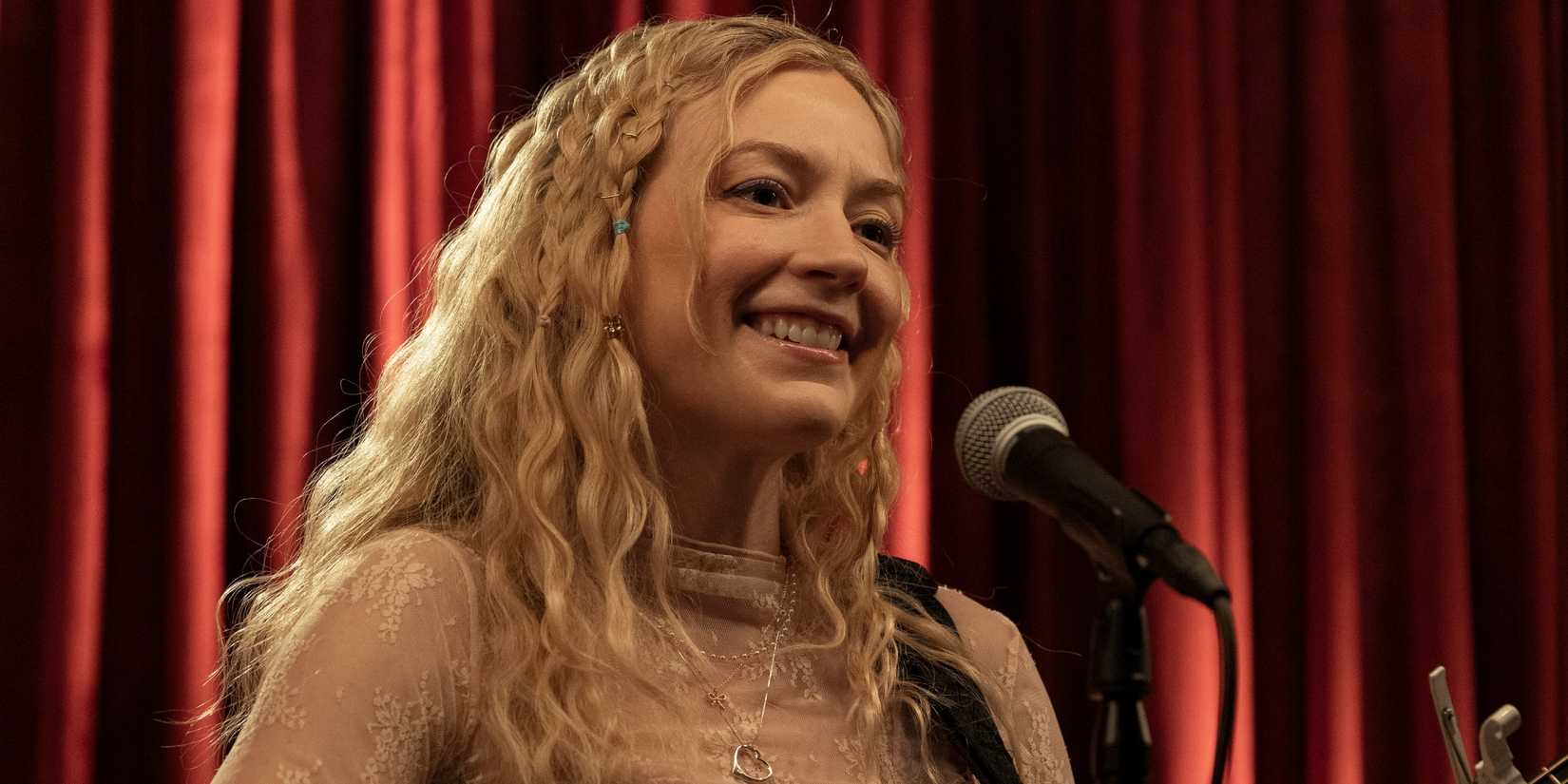 Emily Kinney as Beth standing at a microphone while performing in a bar in The Walking Dead: Dead City
