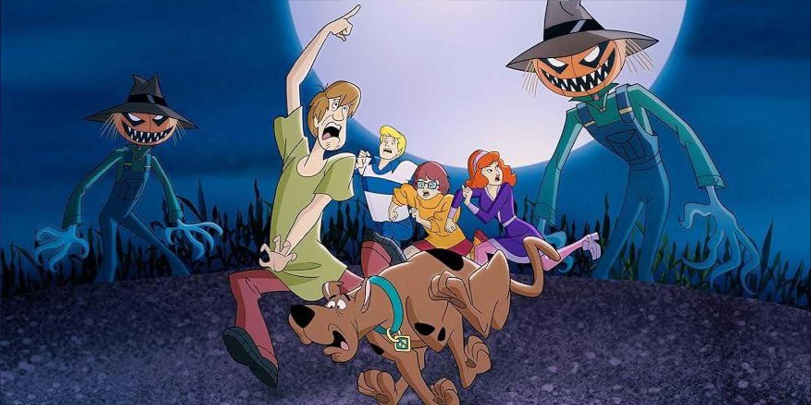 Scooby-Doo and the gang run from two pumpkin-headed scarecrows in the "A Scooby-Doo Halloween" episode of 'What's New, Scooby-Doo?'