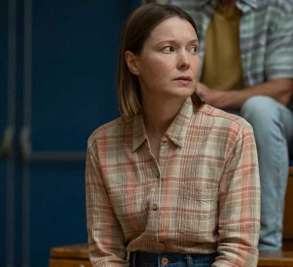 Samantha Sloyan as Margaret White sitting in a school gymnasium in Carrie.