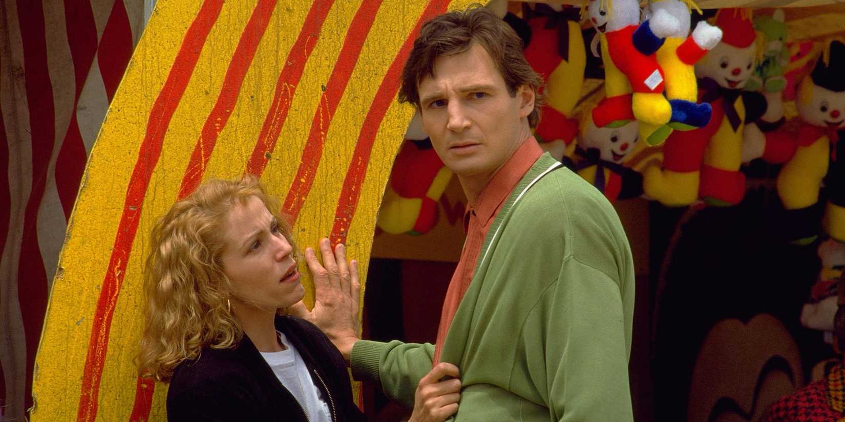 Frances McDormand and Liam Neeson stand at a carnival game booth in Sam Raimi's Darkman