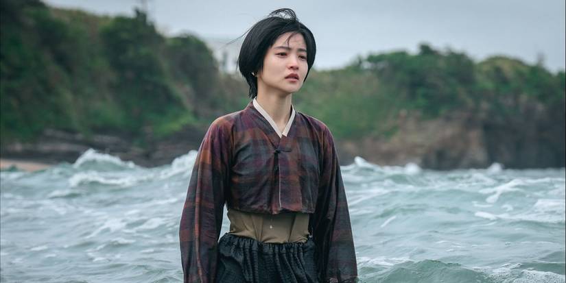 Kim Tae-ri stands in ocean waves looking desolate in the drama Jeongnyeon: The Star Is Born