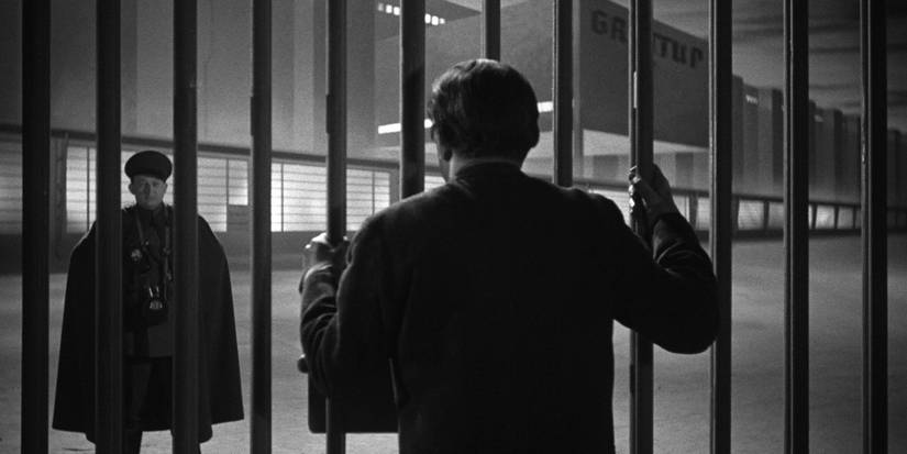 A man looking at a decorated soldier from behind prison bars in Czech film 'Krakatit' (1948)