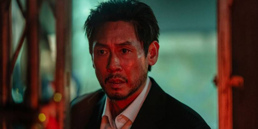 Actor Sul Kyung-gu looking anxious in a dark suit under intense red lighting in Mousetrap