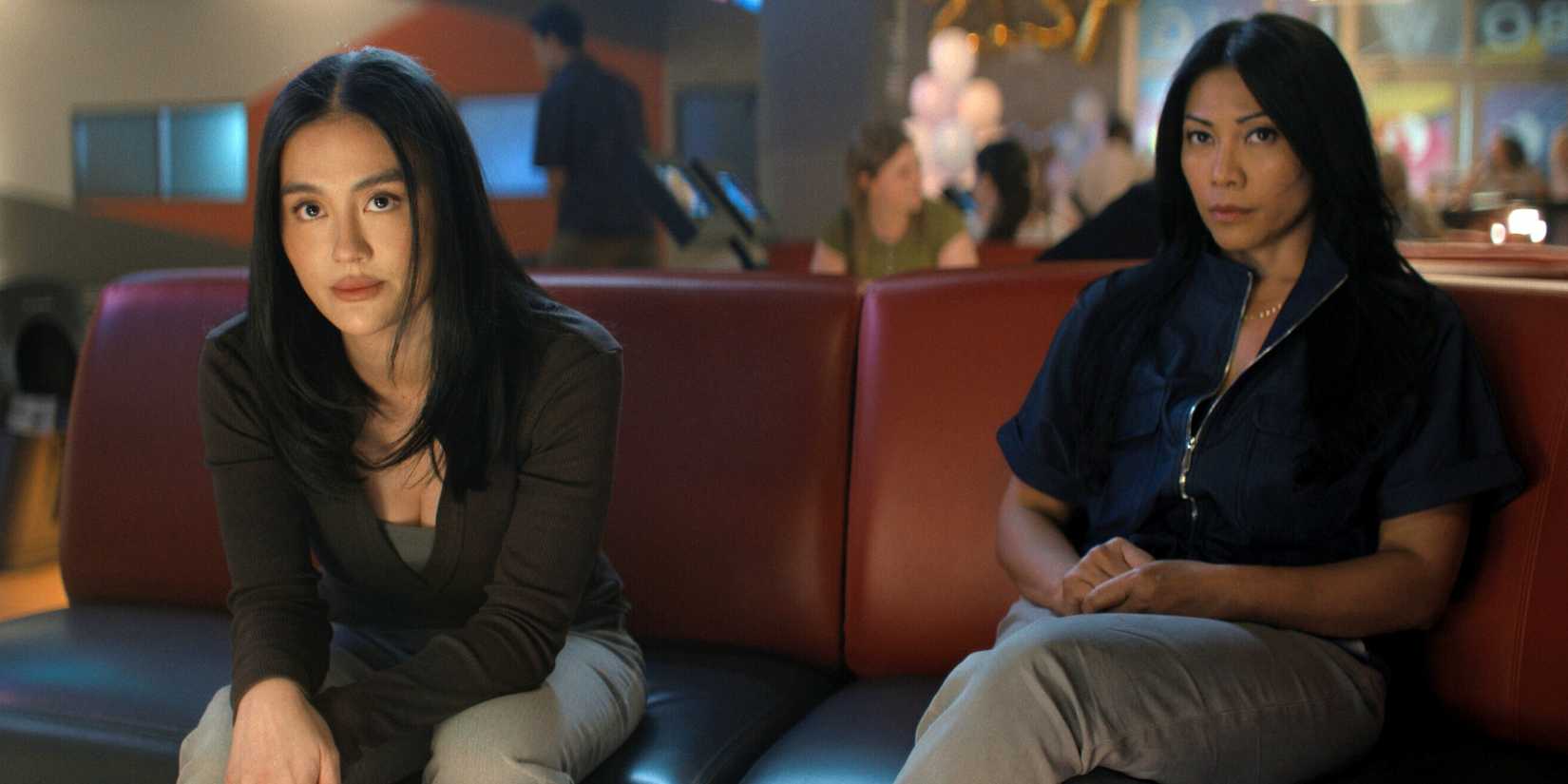 Agnez Mo as Lila Hoth and Anggun as Amisha sitting on a bench in a bowling alley in Reacher Season 4