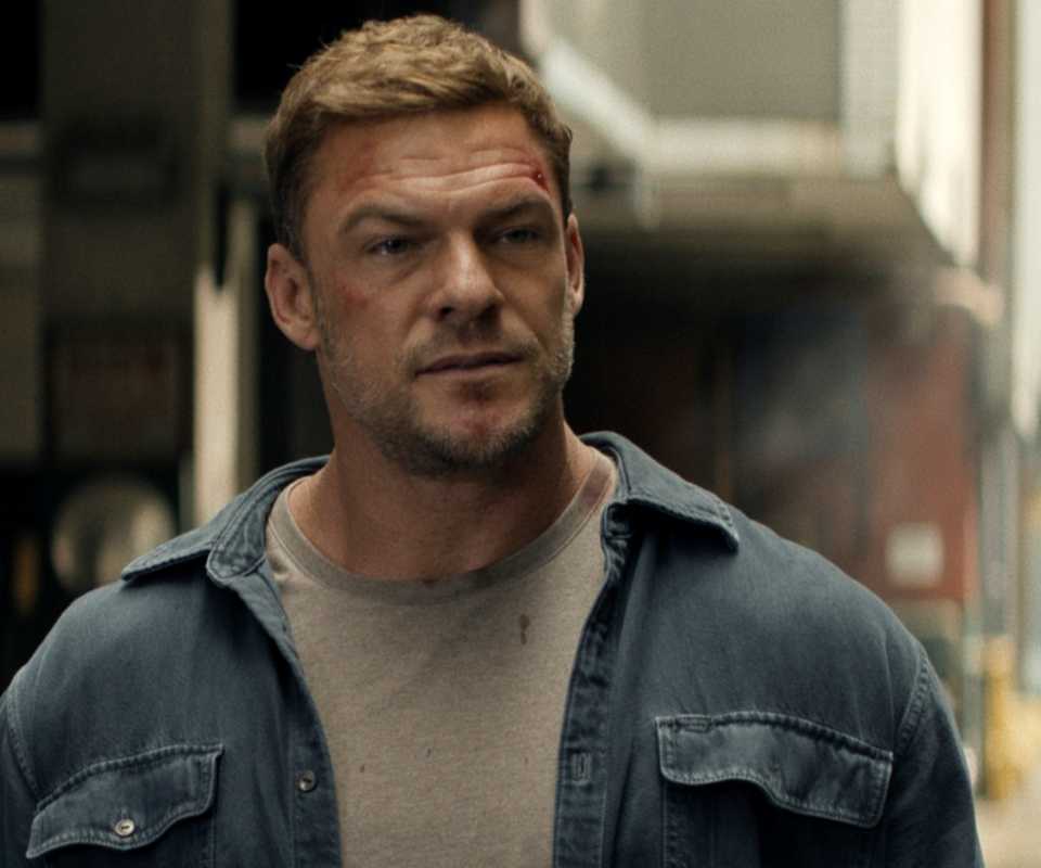 Alan Ritchson standing outside on the street in Reacher Season 4