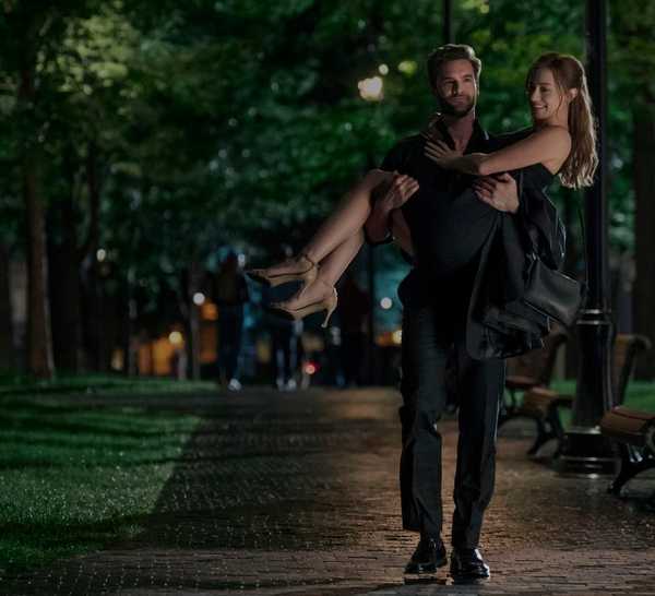 Tom Bateman carrying Lili Reinhart in The Love Hypothesis