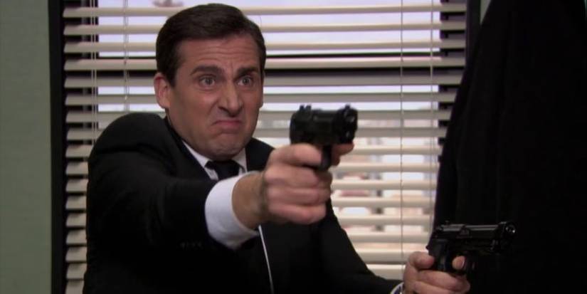 Michael Scott (Steve Carell) pointing two guns offscreen in 'The Office' Season 7 episode "Threat Level Midnight'