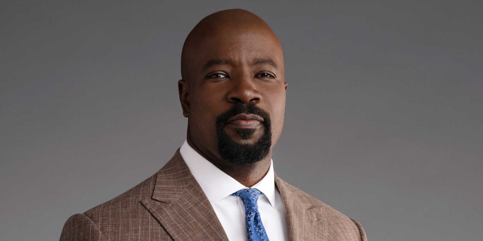 Mike Colter as Michael Price in a suit with a blue tie in a promo shot for Cupertino