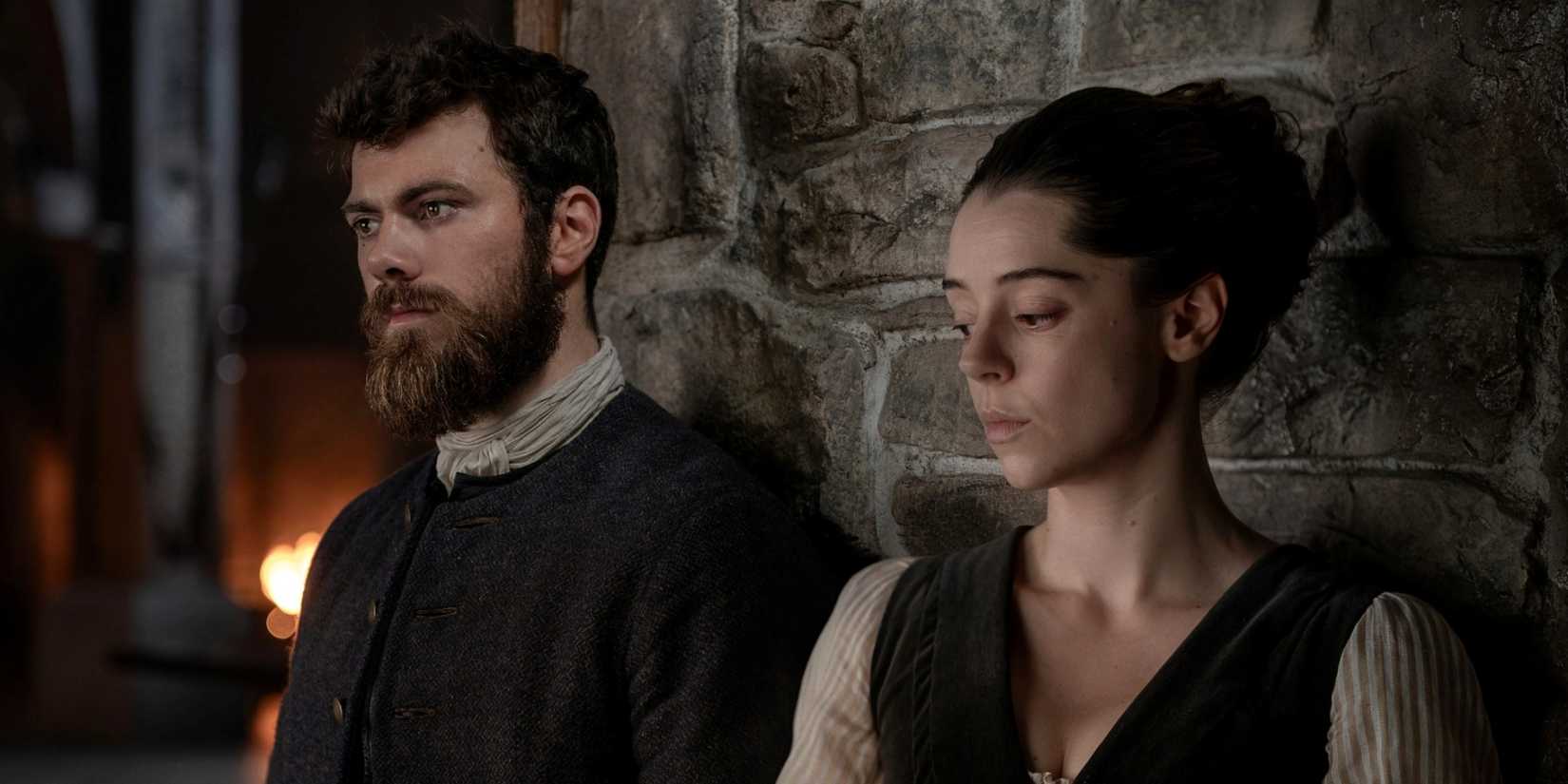 Sam Retford as Dougal leaning against a wall next to Bobby Rainsbury as Maura in Outlander: Blood of My Blood