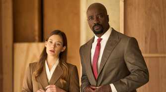 Mike Colter as Michael Price standing next to Rachel Keller as Olivia Siffre in their office in Cupertino