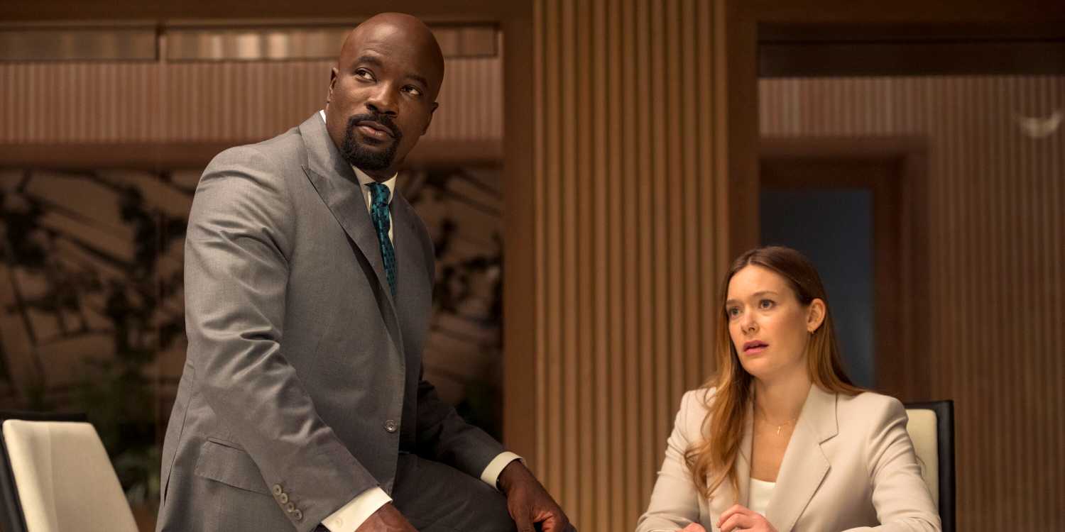 Mike Colter as Michael Price sitting on a table next to Rachel Keller as Olivia Siffre in Cupertino