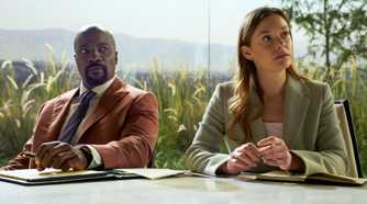 Mike Colter as Michael Price sitting next to Rachel Keller as Olivia Siffre in their office in Cupertino