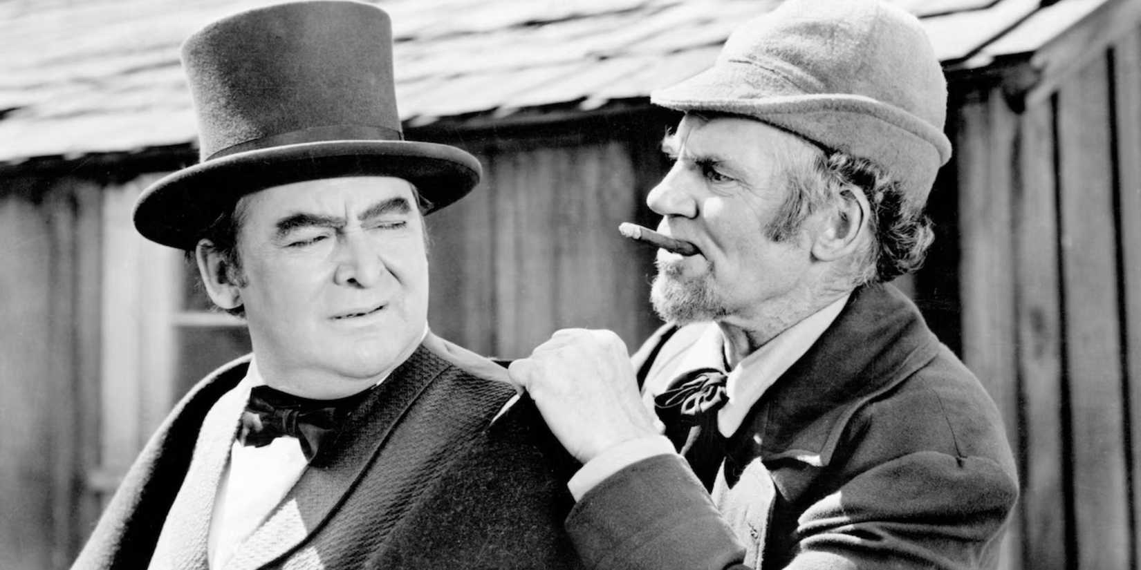 Edward Arnold looking back at Walter Huston who is hanging on his shoulder in The Devil and Daniel Webster (1941)