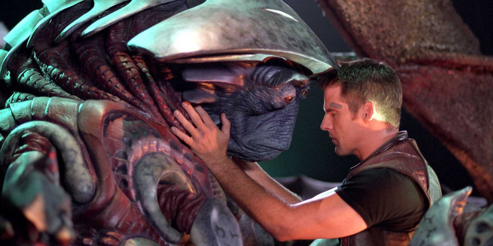 An alien and a man leaning towards each other in 'Farscape: The Peacekeeper Wars'