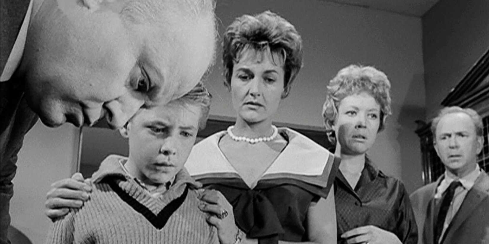 Larry Gates, Michael Burns, Peggy Stewart, Jo Helton and Jack Albertson standing together listening to a radio broadcast in The Twilight Zone episode The Shelter
