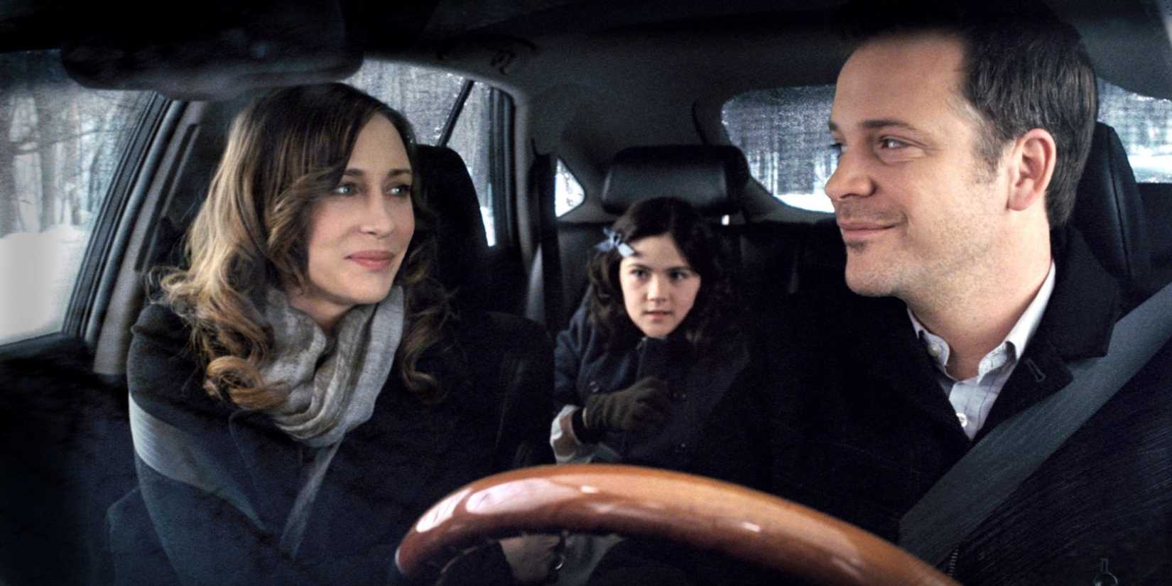 Kate and John smiling at each other in the car in Orphan.