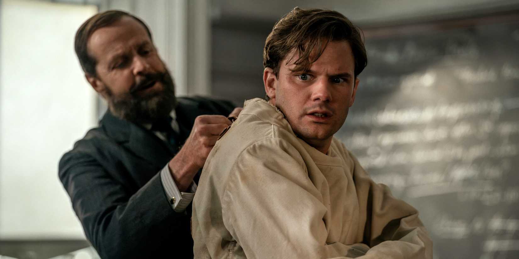 Jeremy Irvine as Henry getting buckled into a straightjacket in Outlander: Blood of My Blood Season 2