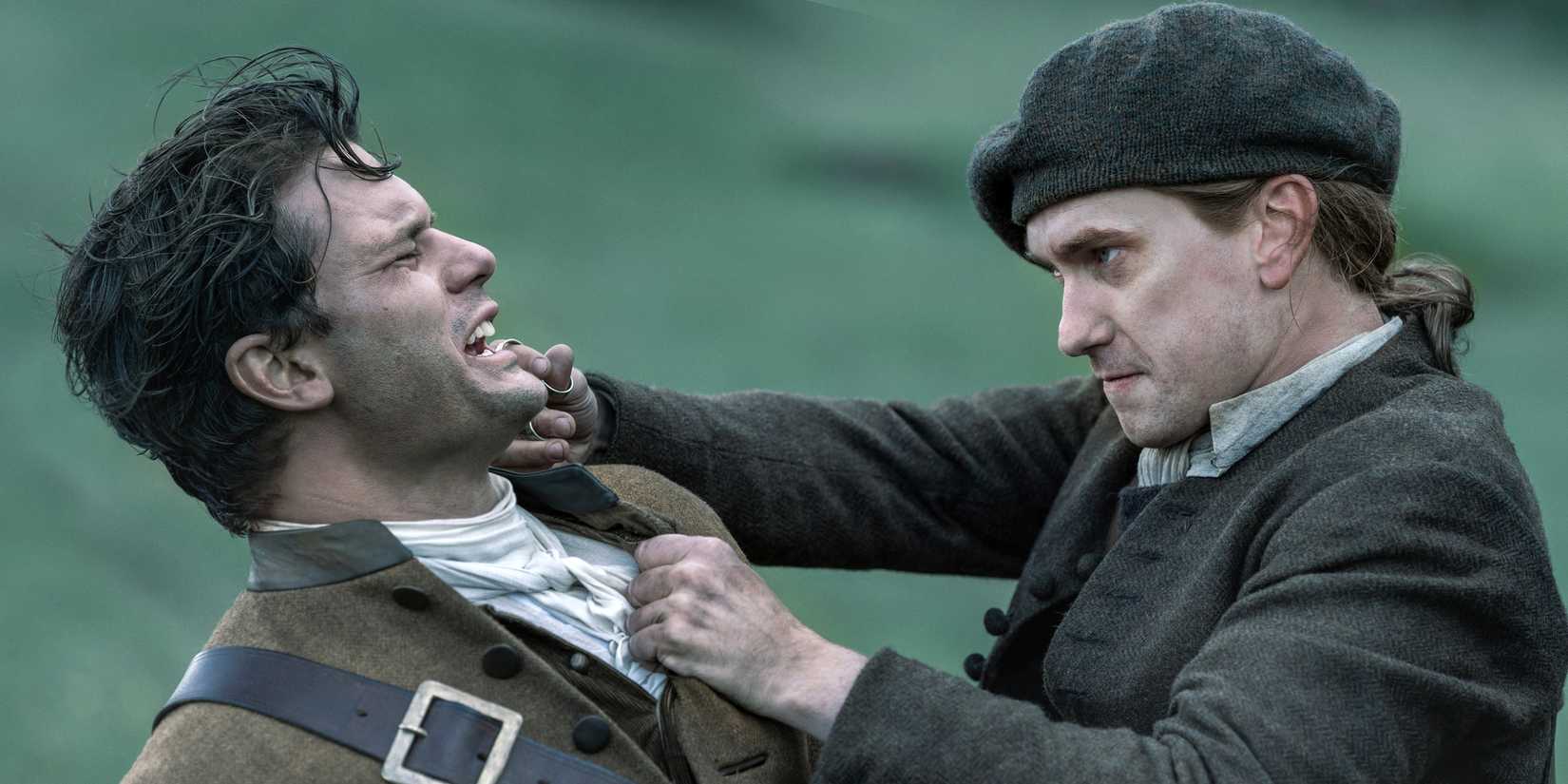 Terence Rae as Arch Bug grabbing Jeremy Irvine as Henry in Outlander: Blood of My Blood Season 2