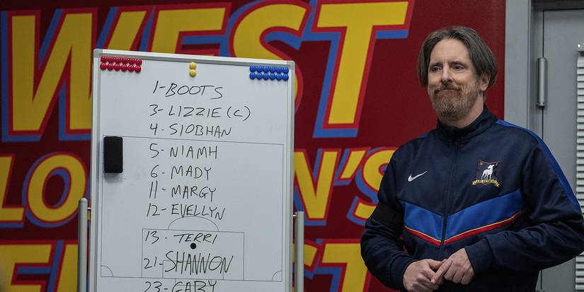Coach Beard standing beside a white board in Ted Lasso.