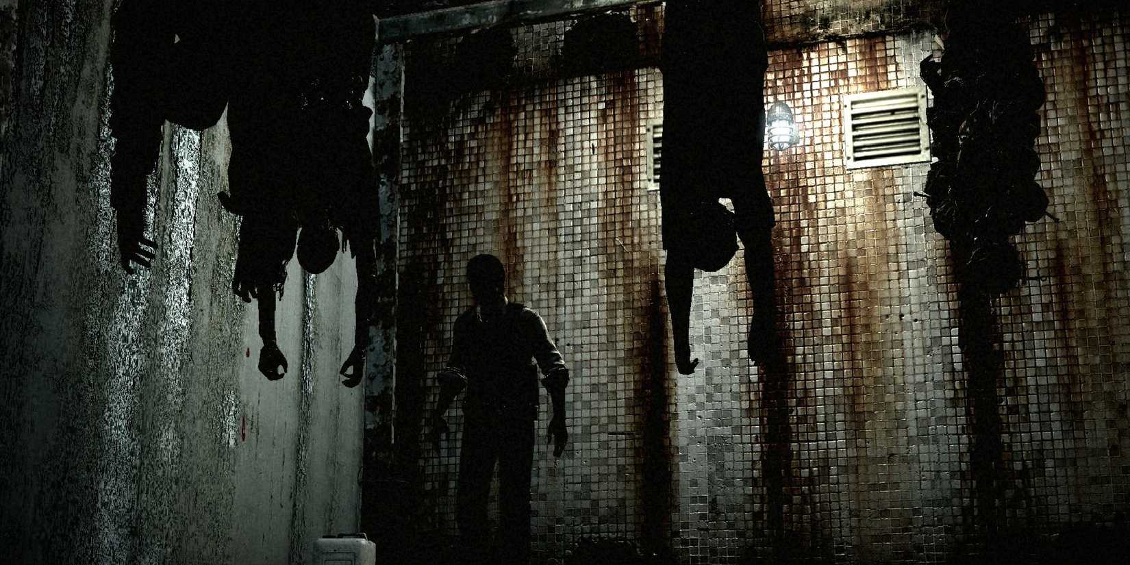 A man in a dark room seeing two men hanging from the ceiling in The Evil Within 2