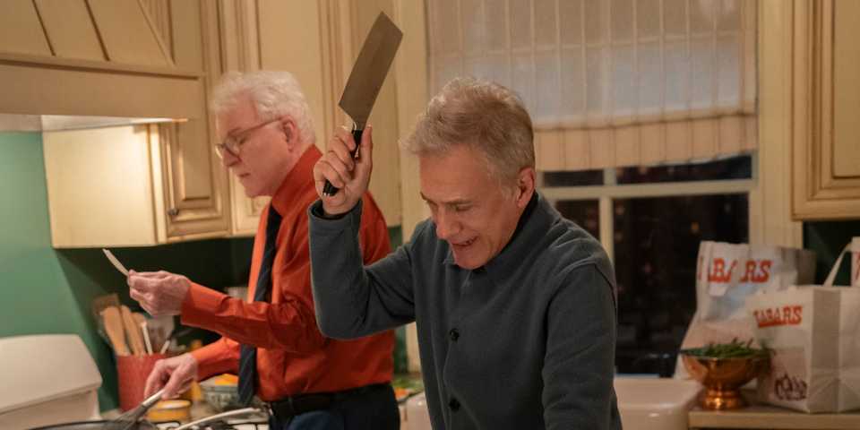 Bash holding a meat clever with Charles in the background reading a recipe in Only Murders in the Building.